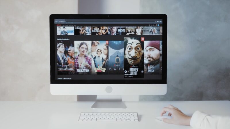 Netflix homepage displayed on a desktop computer beside a keyboard and mouse.
